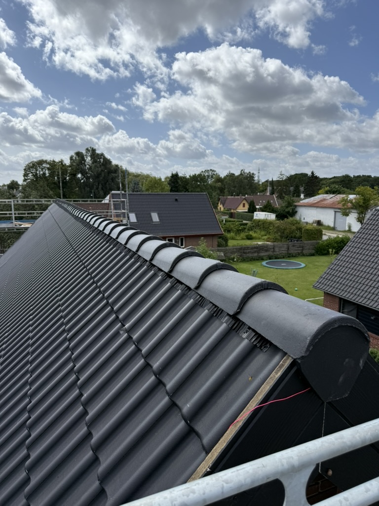 Nye mørke betontagsten set fra rygningen mod blå himmel med hvide skyer