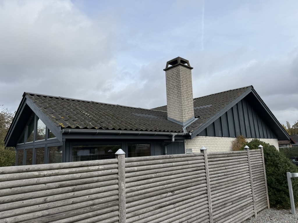 Parcelhus med mørke betontagsten og muret skorsten